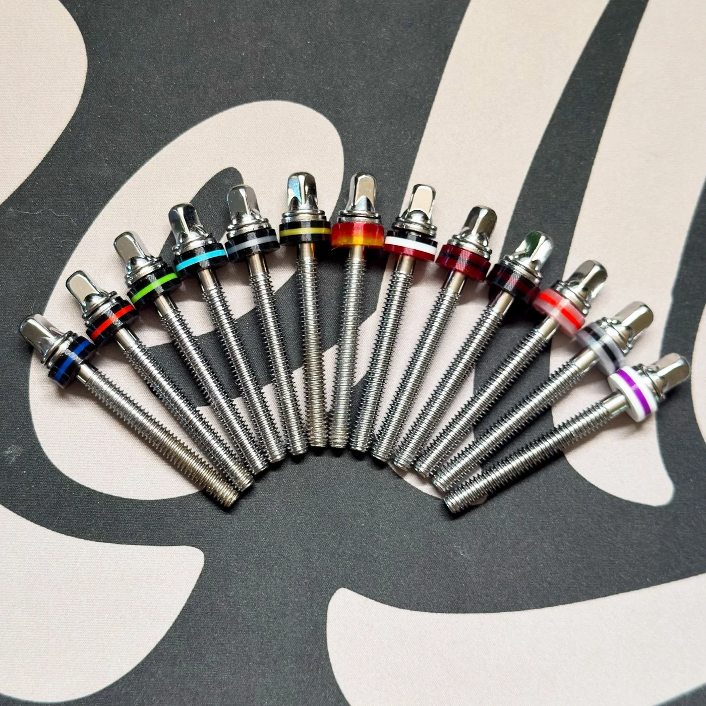 A fan of chrome tension rods fitted with Kelley Drums washers in different color combinations